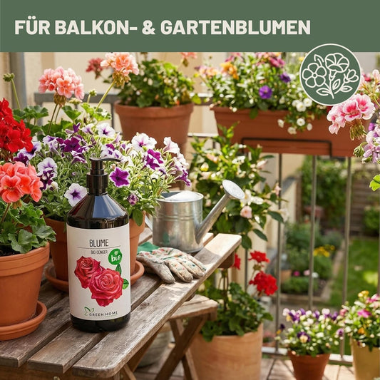 Green Home Bio Dünger Blumen 1 Liter auf einem Balkon zwischen blühenden Topfpflanzen und Gießkanne