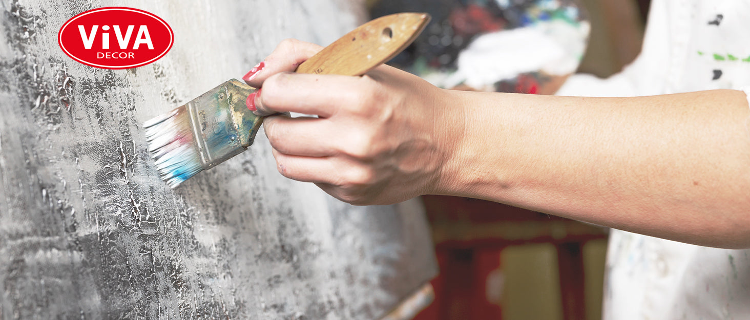 Hand trägt Metallfarbe mit Pinsel auf strukturierte Oberfläche auf – kreative Anwendung