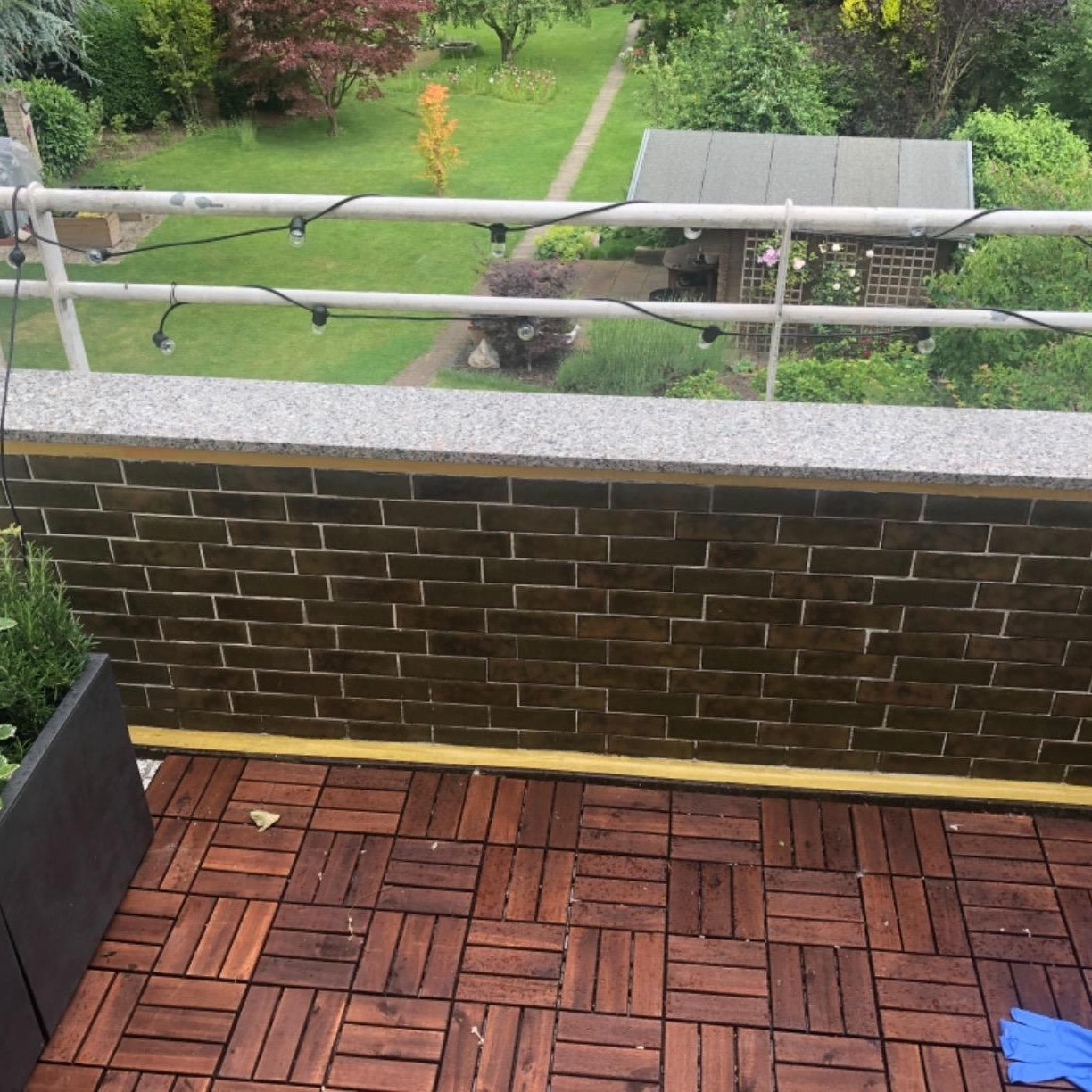 Balkon mit dunklen Wandfliesen und Holzfliesenboden als Vorheransicht für die Anwendung von ColourPlus Fliesenlack.