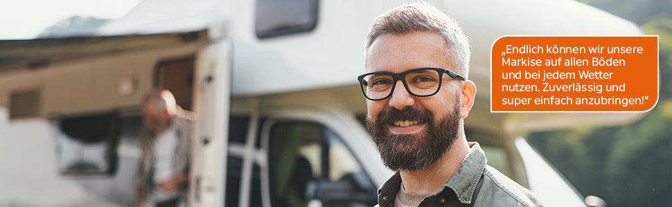 Mann steht lächelnd vor einem Camper mit ausgefahrener Markise und berichtet über einfache Nutzung und zuverlässigen Halt der Cosador Markisenhalterung.