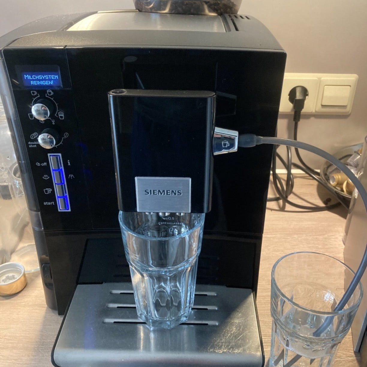Siemens Kaffeevollautomat waehrend der Reinigung des Milchsystems mit angeschlossenem Schlauch und Reinigungsprogramm.