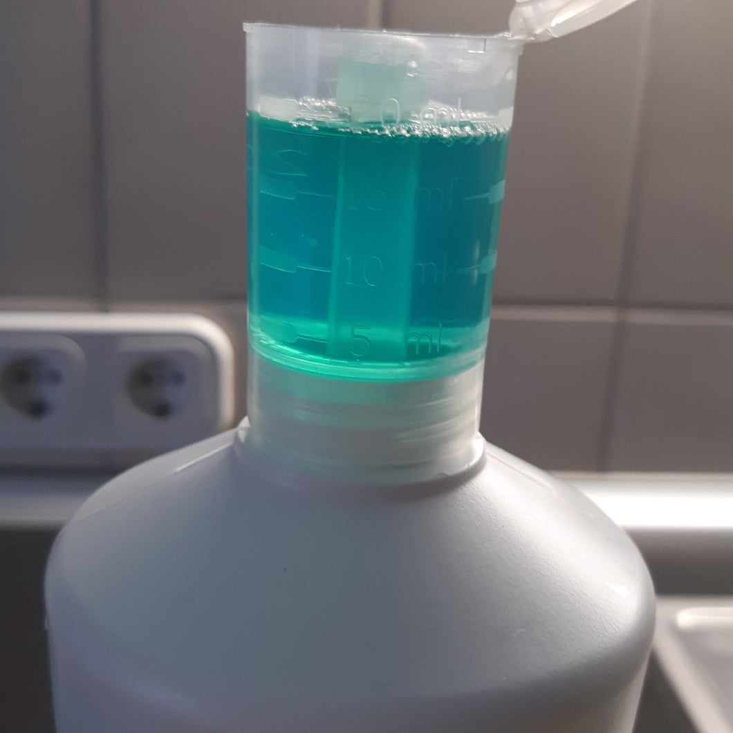 Detailaufnahme des Dosierdeckels mit grünem Reinigungskonzentrat und Milliliter-Skala zur genauen Dosierung.