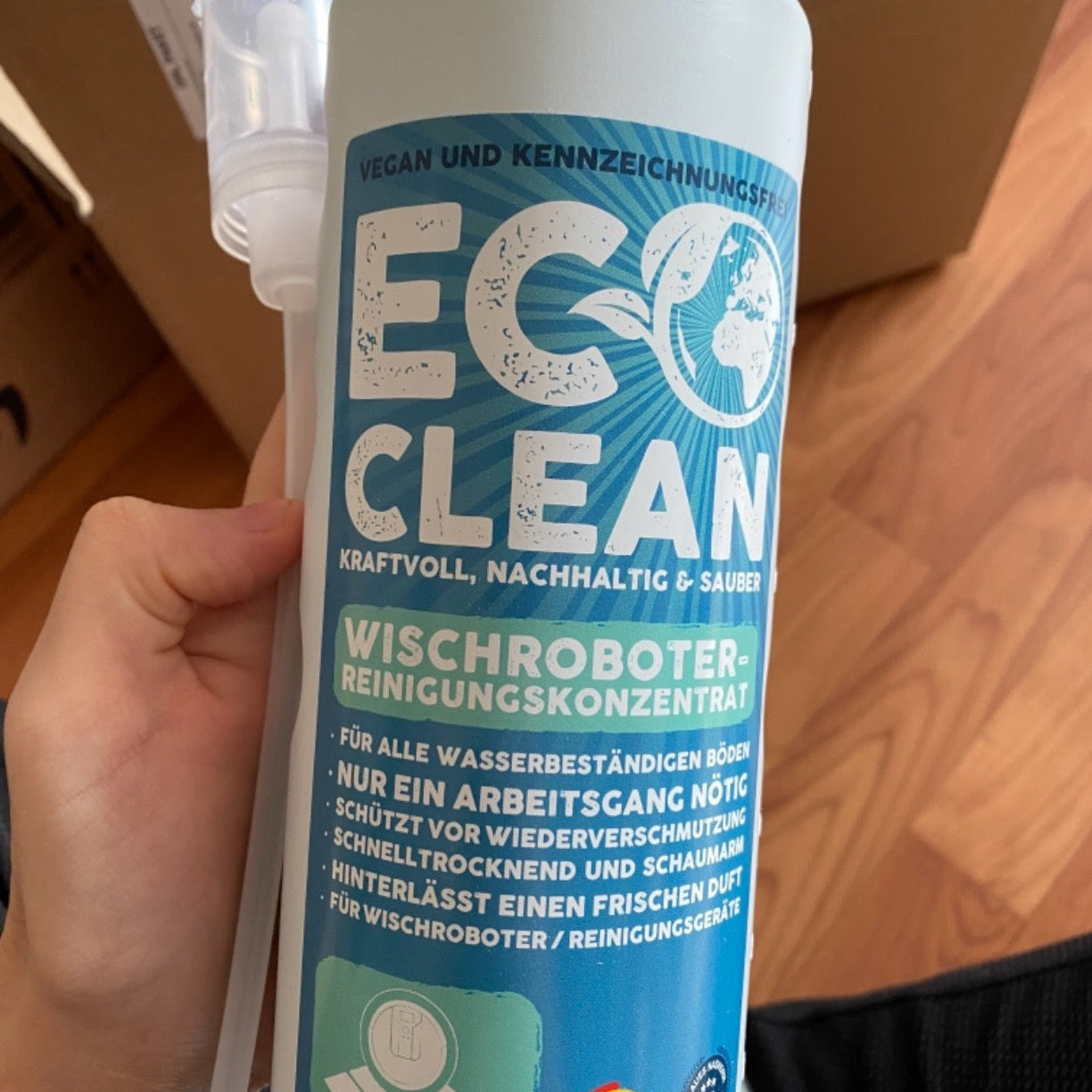 Eco Clean Wischroboter Reinigungskonzentrat 1 Liter Flasche in der Hand gehalten mit sichtbarem Produktlabel.