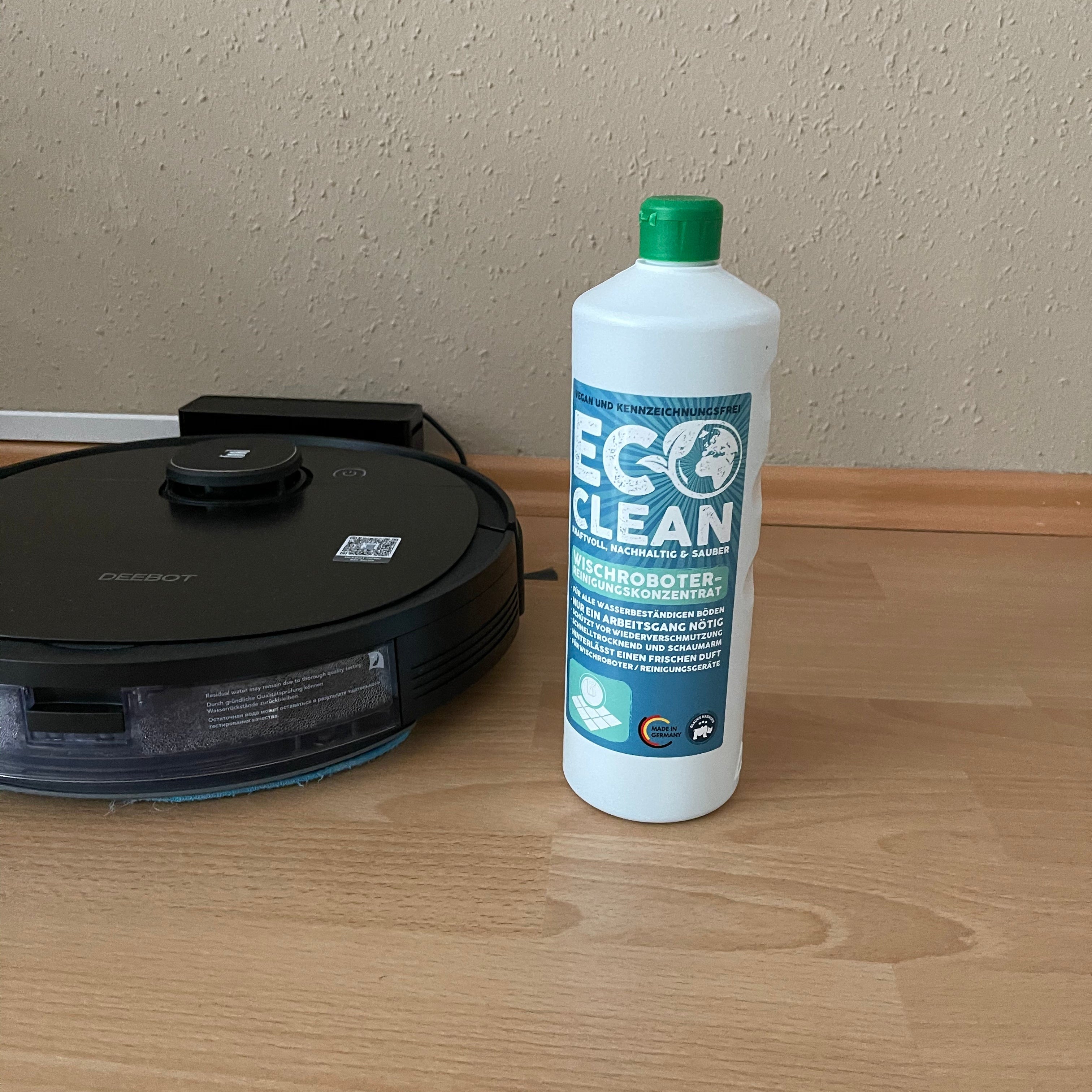 Eco Clean Wischroboter Reinigungskonzentrat 1 Liter neben einem Saug- und Wischroboter auf Holzboden platziert.
