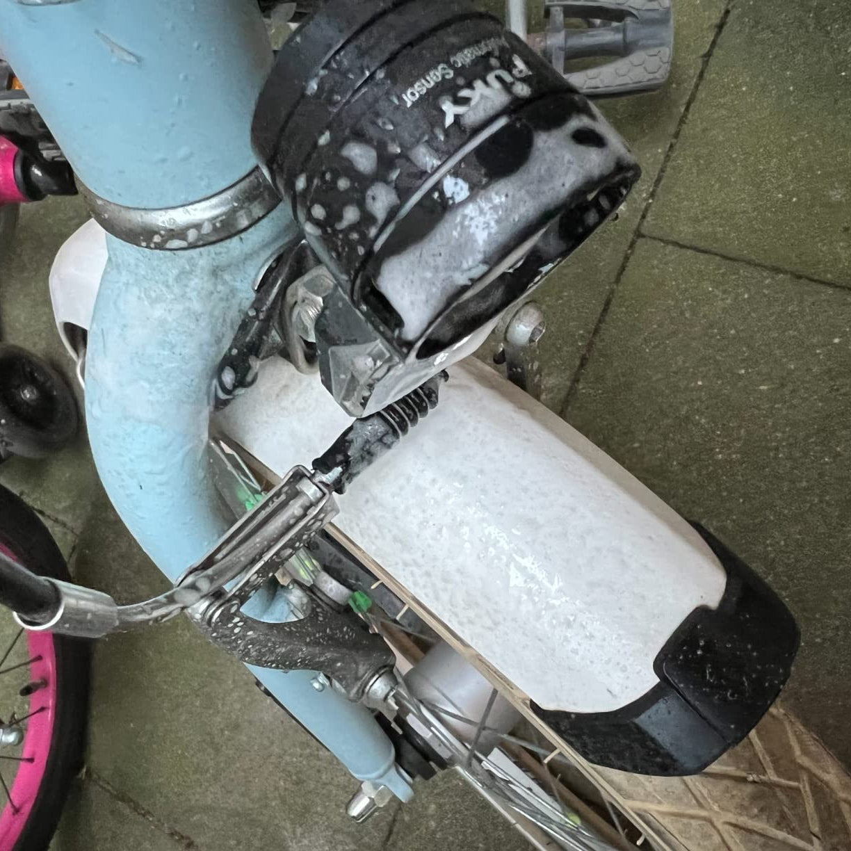 Detailaufnahme eines Fahrradschutzblechs und Scheinwerfers mit aufgetragenem Reinigungsschaum während der Anwendung.