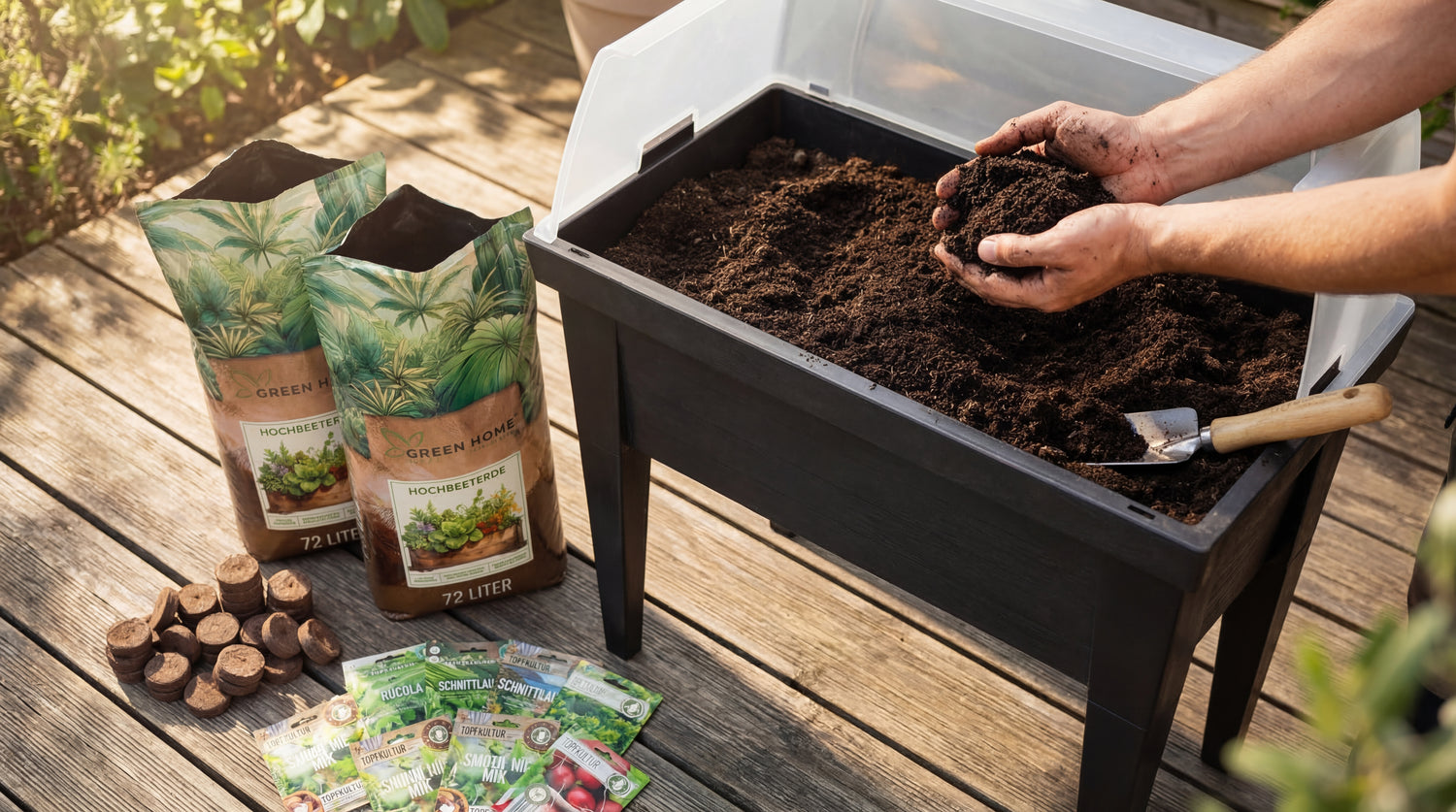 Hände füllen Erde in ein Green Home Hochbeet auf einer Holzterrasse, daneben Erdebeutel, Samen und Quelltabletten aus dem Set.