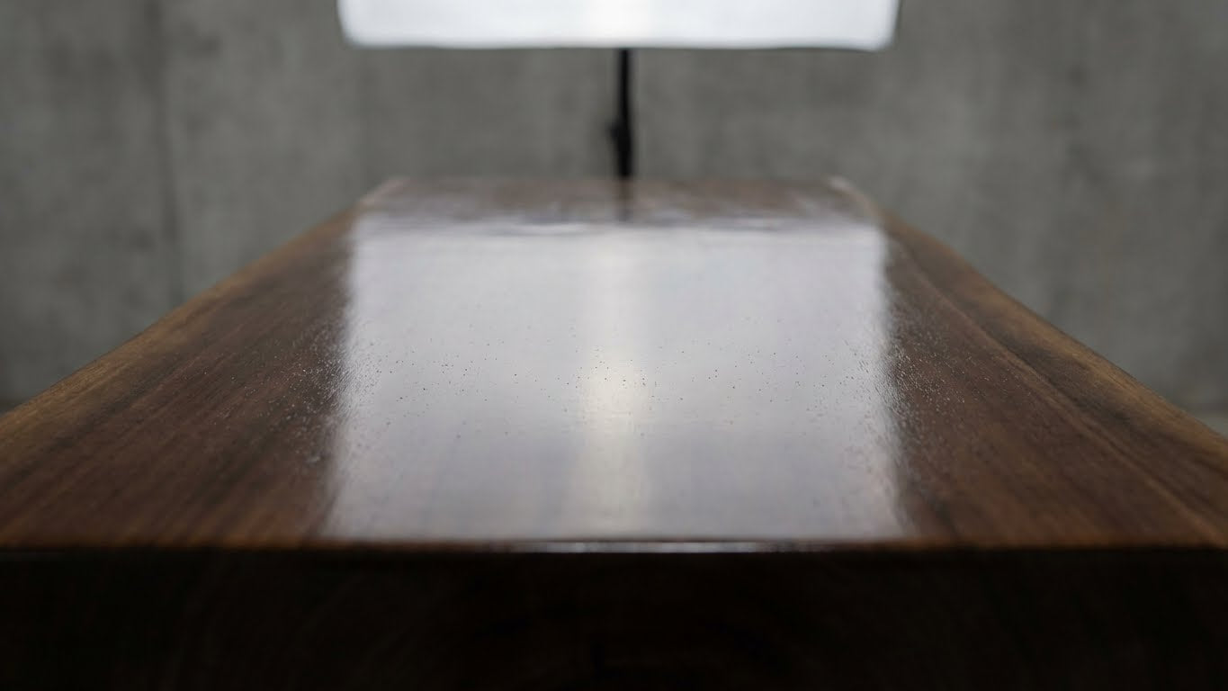 Detailaufnahme einer dunklen Holzoberflaeche mit stark glaenzender Lackbeschichtung