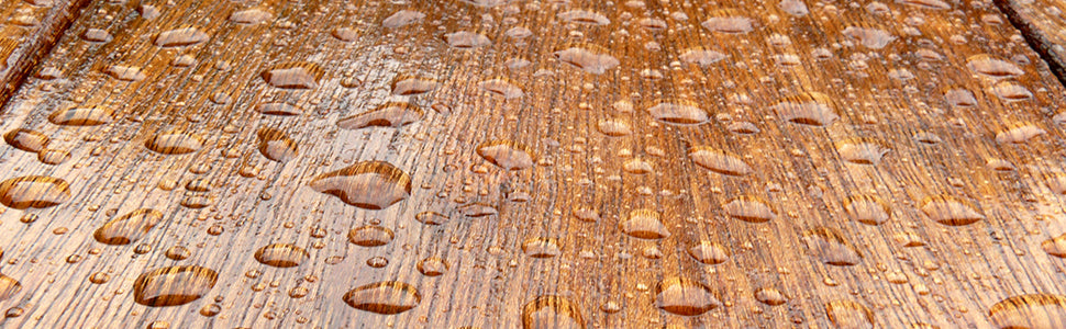 Holzoberfläche mit Wassertropfen, die die wasserabweisende Wirkung einer behandelten Holzstruktur zeigen