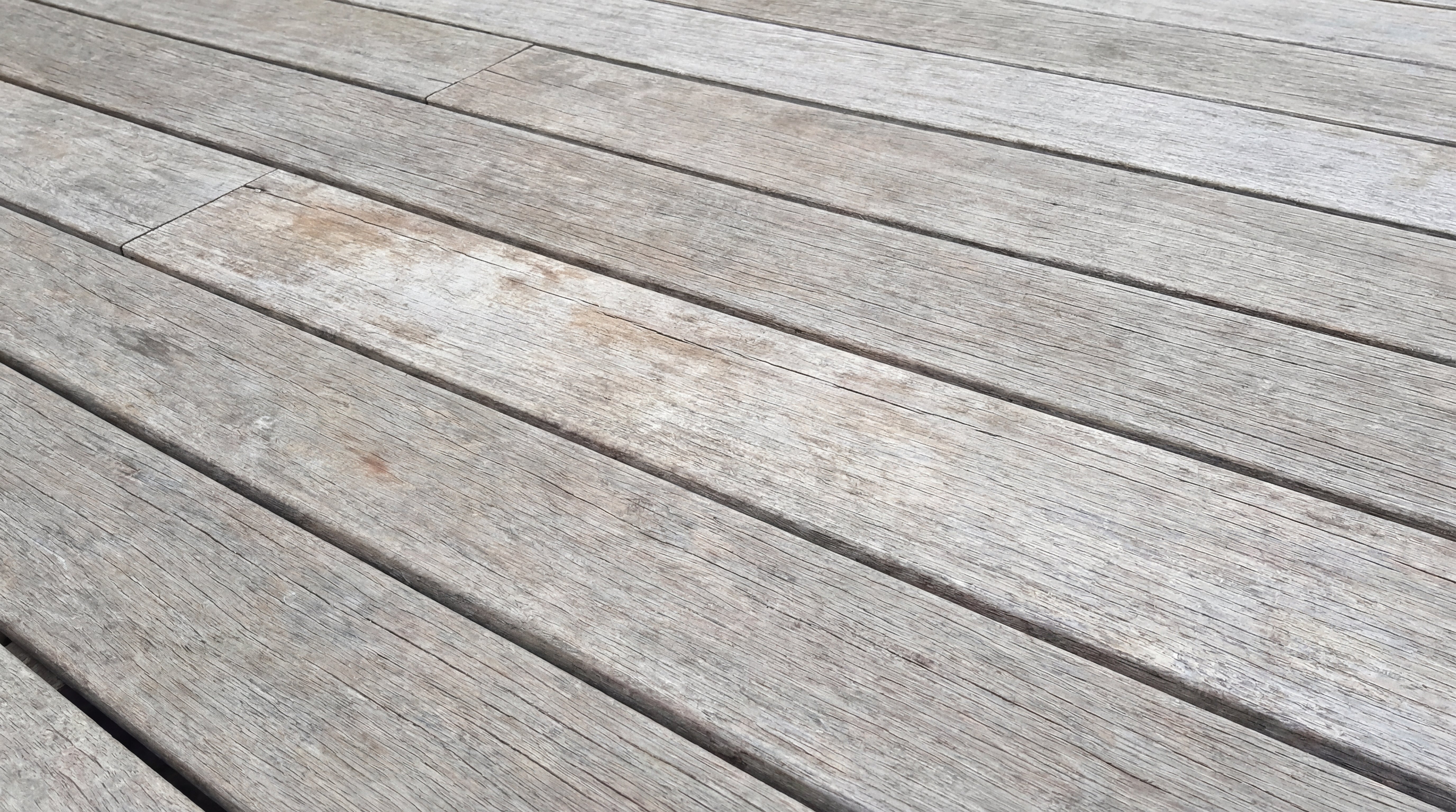 Verwitterte und vergraute Holzterrasse mit matter Oberfläche und sichtbaren Gebrauchsspuren.