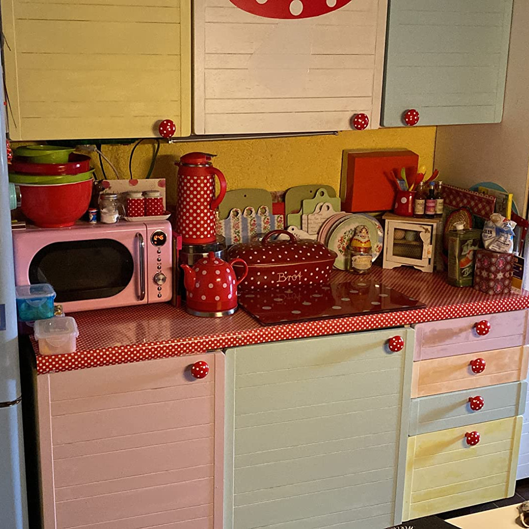 Küchenmöbel in Pastellfarben mit roten gepunkteten Griffen und Accessoires im verspielten Retro Stil.