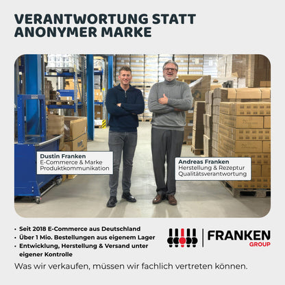 Zwei Mitarbeiter stehen in einer Lagerhalle zwischen Paletten und Kartons eines Versandlagers