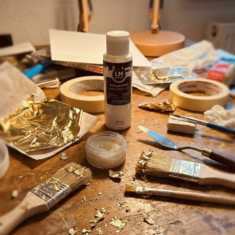 LM Kreativ Anlegemilch 70 ml auf einem Arbeitstisch mit Blattgold, Pinseln und Werkzeugen zur Vergoldung