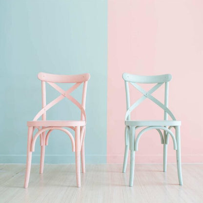 Zwei Holzstuehle in Pastell Rosa und Mint gestrichen mit LM Kreativ Chalky Moebelfarbe vor zweifarbigem Hintergrund in passenden Pastelltoenen.