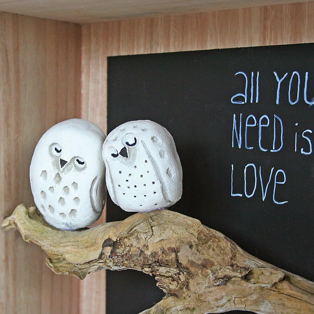 Mit LM Kreativ Knetbeton gefertigte Deko-Eulen auf einem Holzast vor einer Tafel mit Schriftzug.