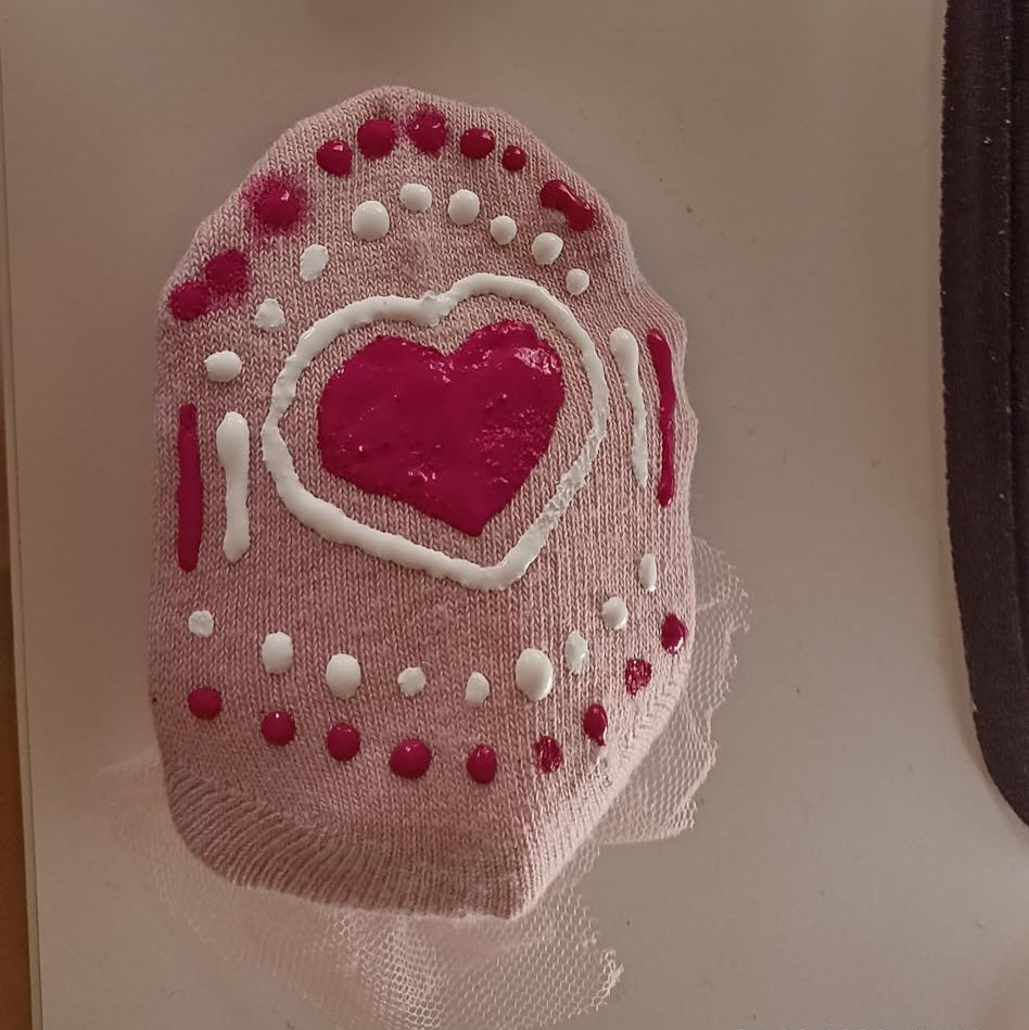 Babysocke mit rotem Herzmotiv und weissen sowie roten rutschfesten Stopperpunkten, gestaltet mit der LM Kreativ Socken Stopper Textilfarbe.