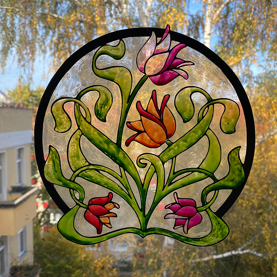 Rundes Window Color Fensterbild mit Blumenmotiv in kräftigen Farben, angebracht an Fensterscheibe.
