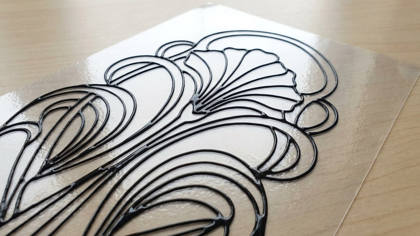 Ornamentales Blumenmotiv mit schwarzer Kontur auf transparenter Folie gestaltet mit LM Kreativ Window Color Konturfarbe.