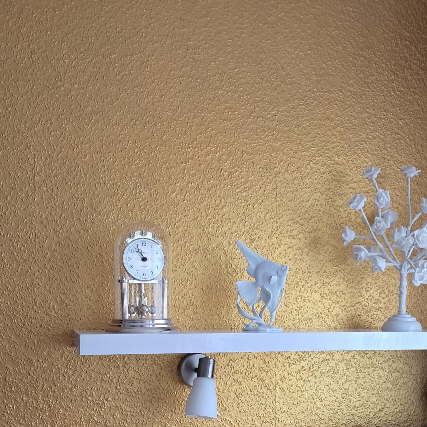 Detailaufnahme einer Gelb-Gold Metallic Wandfarbe mit feiner Struktur und schimmerndem Lichteffekt.