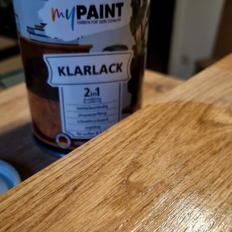 Detailaufnahme einer mit My Paint 2in1 Klarlack behandelten Holzoberflaeche neben der Produktdose