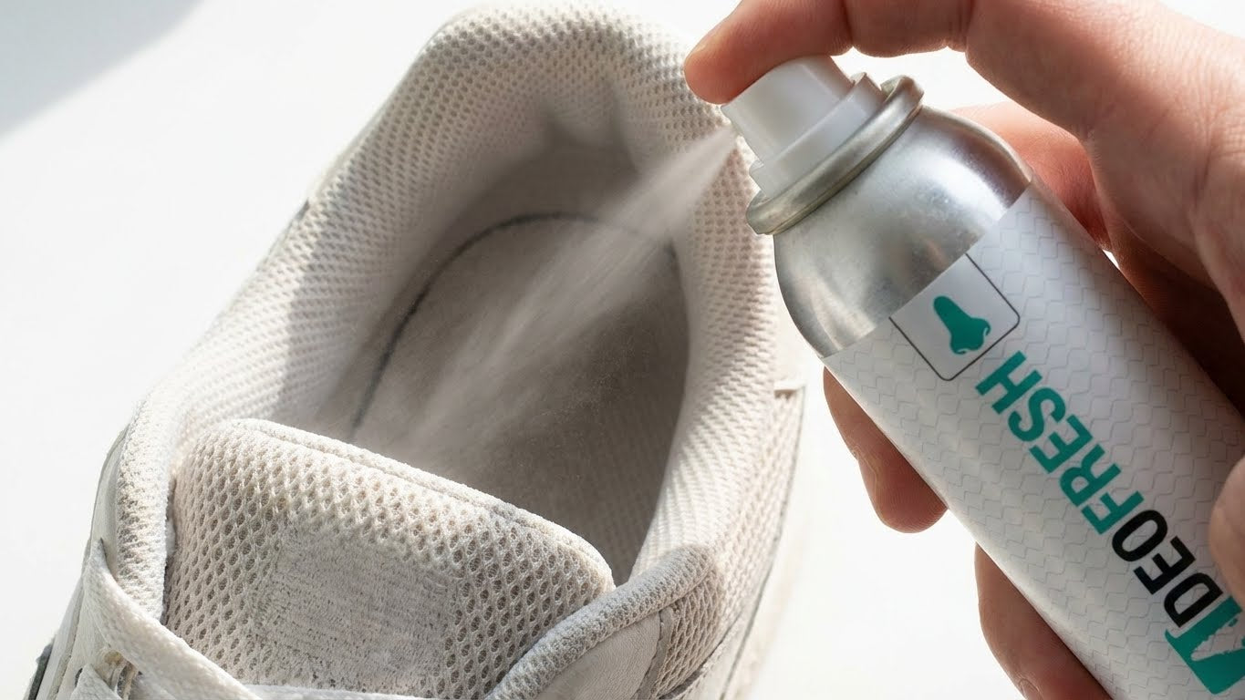 Hand sprüht Sneaker Cleaner Deofresh in das Innere eines weißen Sneakers zur Geruchsneutralisierung.