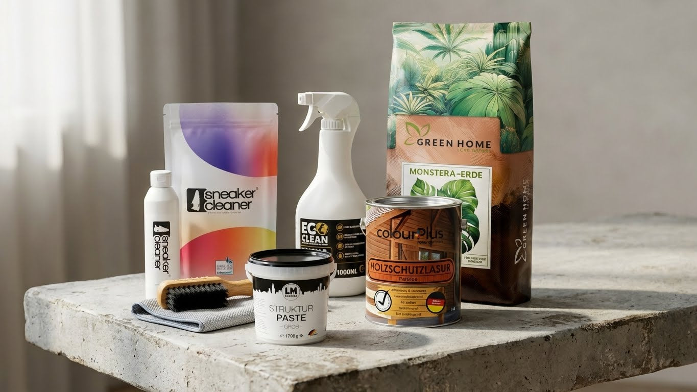 Mehrere Produkte wie Sneaker Cleaner, ECO Clean Reiniger, LM Strukturpaste, ColourPlus Holzschutzlasur und Green Home Monstera-Erde stehen gemeinsam auf einem Betontisch vor neutralem Hintergrund.