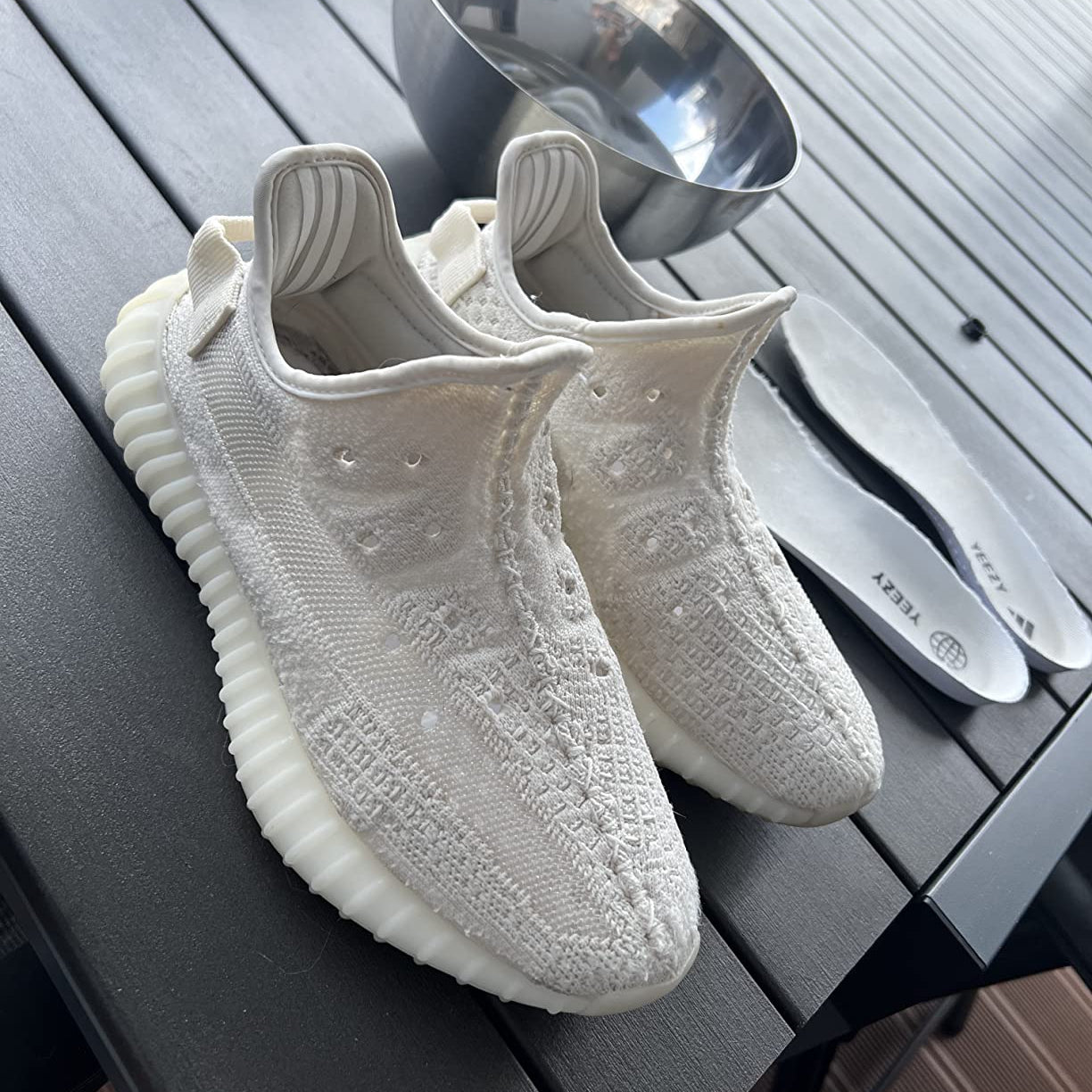 Gereinigte weiße Mesh-Sneaker neben Einlegesohlen und Schüssel als Beispiel für die Anwendung des Sneaker Cleaner Reinigungssets.