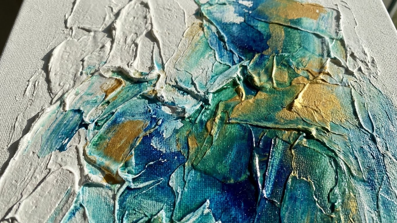 Detailaufnahme einer strukturierten Leinwand mit weißer Strukturpaste und blau-goldenen Farbeffekten.