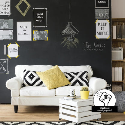 Schwarz gestrichene Tafelflaeche im Wohnzimmer mit Kreidezeichnungen und Zitaten hinter einem Sofa